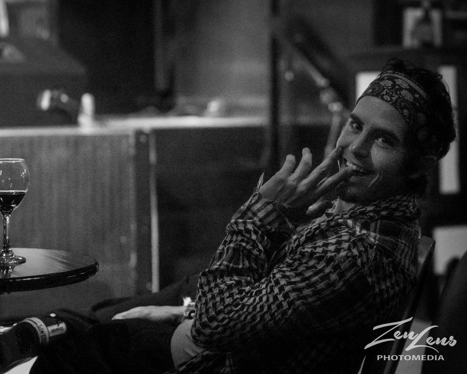 Cam "the" Poet sitting back with a glass of wine after a show, in black and white
